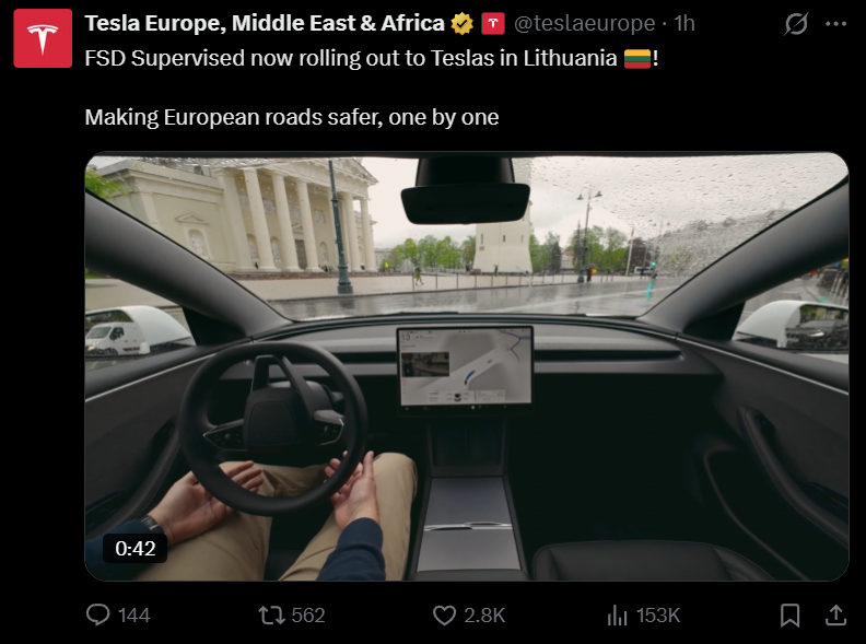 Image - Not an Fsd Tracker Tesla Interior View from the Driver’s Seat with a Large Center Touchscreen and Steering Wheel, Rainy City Street Visible Through the Windshield.